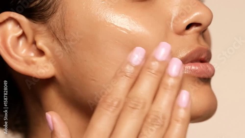 A woman applying skincare product to her face with her hand