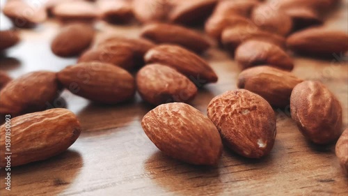 A close-up video shot of sliced almonds slowly pouring onto a wooden table, creating a natural and appetizing pile. 