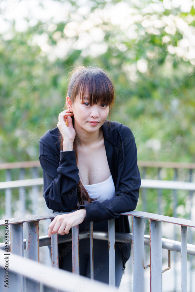 Fototapeta premium Portrait of beautiful asian Young woman in Black robe sportswear working out outside. training on public equipment in outdoor at park. concept Exercise Healthy lifestyle.