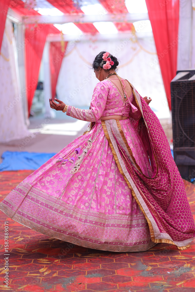 Naklejka premium Indian Woman in Traditional Pink Lehenga and Dupatta at Wedding Venue