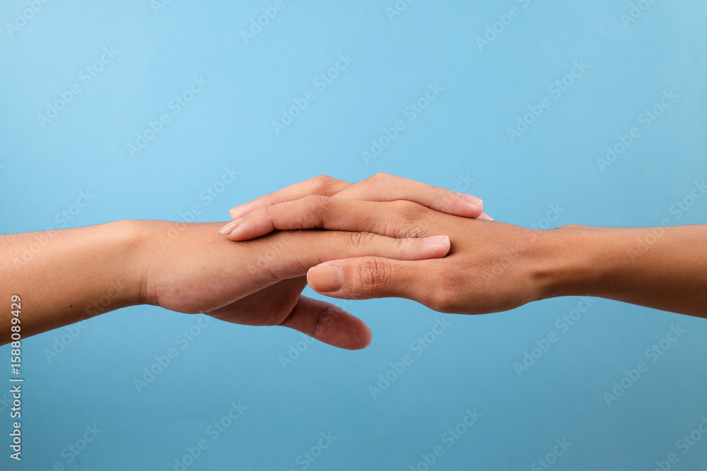 Two Hands Resting Gently On Each Other Isolated On Blue Background Two Hands Resting Gently On Each Other Isolated On Blue Background