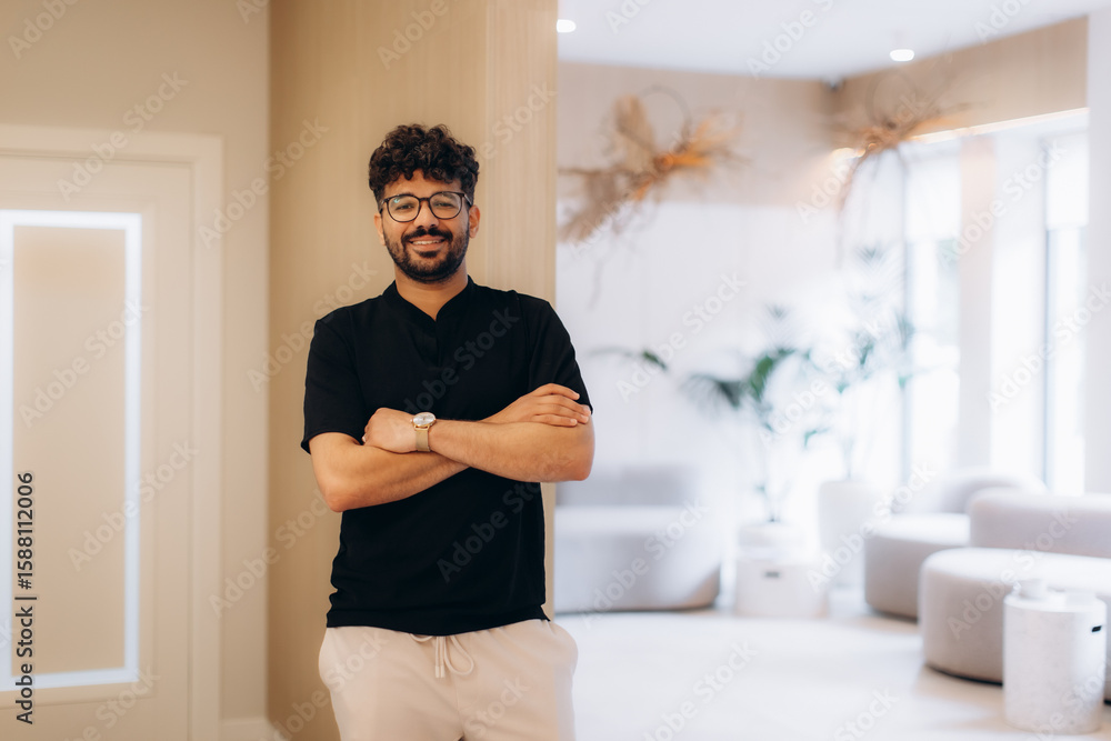 Confident businessman smiling with crossed arms in modern office lobby Confident businessman smiling with crossed arms in modern office lobby