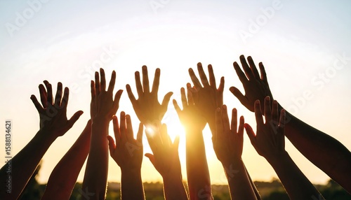 Silhouettes of many hands raised towards the setting sun