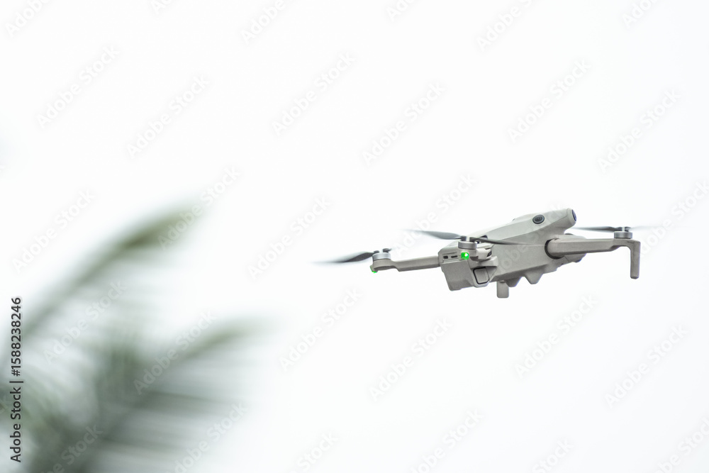 Drone with camera flies in the background of trees and sky. The drone hovers in the air and records Drone with camera flies in the background of trees and sky. The drone hovers in the air and records