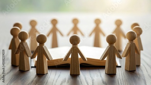 Group of wooden figures holding hands in a circle around Bible — unity in faith and prayer

