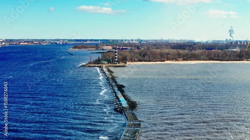 Wallpaper Mural A long stone jetty extends into the water, guiding toward a striped lighthouse on the shore. The scene includes calm waters, distant city skyline, and coastal forest. Torontodigital.ca