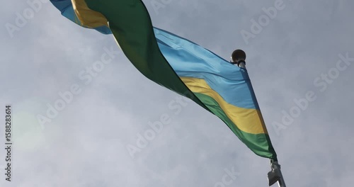 The flag of Rwanda is captured in close-up. The flag of Rwanda, fluttering against the blue sky, is the national symbol of Rwanda. The video is presented in 4K format. Great for news.