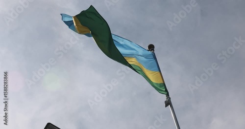 The flag of Rwanda is captured in close-up. The flag of Rwanda, fluttering against the blue sky, is the national symbol of Rwanda. The video is presented in 4K format. Great for news.