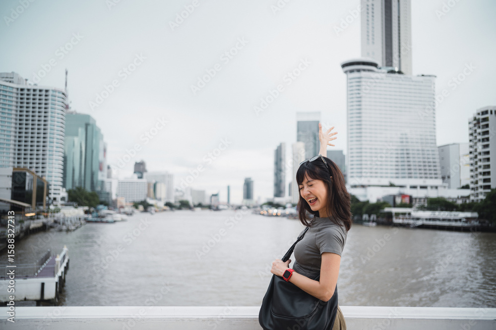 Fototapeta premium Happy young southeast asian woman teenager blogger with smartphone on solo world travel for local cultural experience. Explorer on Chao Phraya river in Bangkok Thailand Asia tourism concept