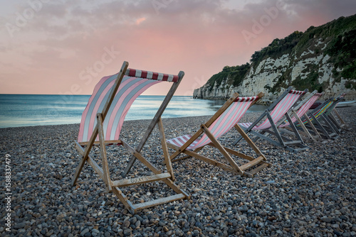 Line of deckchairs billowing in seaside breeze in Devon
