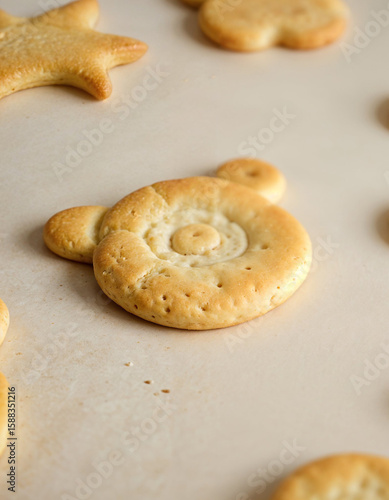 Sweet Treats: A close-up shot of an adorable, freshly-baked biscuit in the shape of a bear, alongside a collection of other delectable, golden-brown pastries. Inviting and tantalizing.