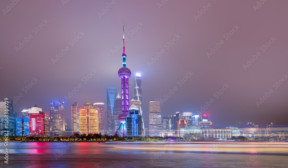 Obraz premium Shanghai colorful skyline with motion speed light of passing ferry in the foreground at night - Shanghai, China