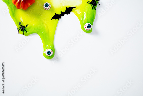 Canvas Print Dripping green slime with scary eyeballs, spiders, bat cutout, and pumpkin on white background