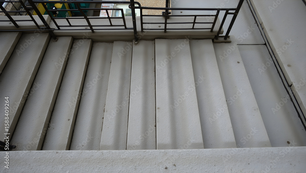 Obraz premium Building Urban stairwell structure with repeating concrete steps and metal guardrails viewed from top down angle