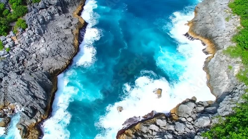 Aerial View of Turquoise Ocean Waves Crashing Against Rocky Coastline Surrounded by Green Vegetation