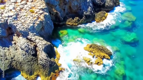 Turquoise ocean waves crashing against rocky coastline with vibrant clear water and rugged cliffs
