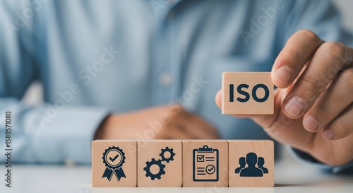 Man holding a wooden block with iso text and other blocks with business icons.