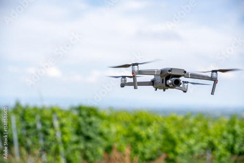 Flying Drone in Vineyard Captured in Sharp Focus – Modern UAV with Camera Hovering Mid-Air, Blurred Green Background, Agricultural Technology and Aerial Photography Concept