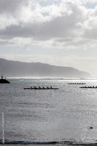 Outrigger canoe paddling at Waialua Bay at the island of Oahu, Hawaii, USA against backlight