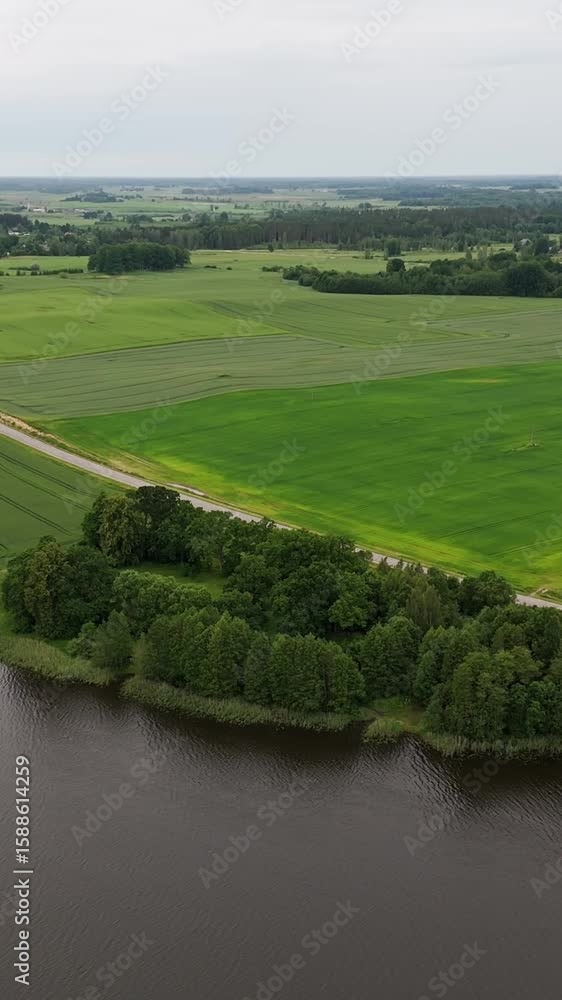 Lush green fields float on water beneath a dramatic cloudy sky, captured vertically Lush green fields float on water beneath a dramatic cloudy sky, captured vertically
