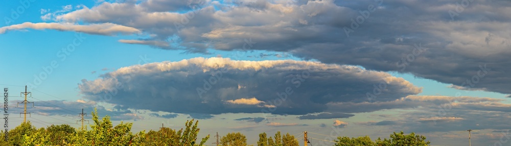 Obraz premium Sky panorama with clouds and blue sky above deciduous trees. Natural background with cloudy sky
