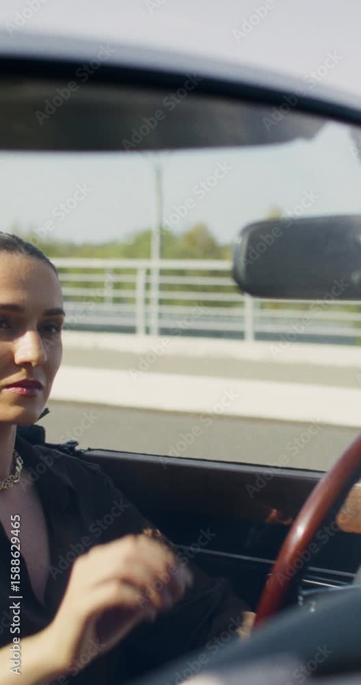 A woman puts on sunglasses while sitting in the driver's seat in a convertible A woman puts on sunglasses while sitting in the driver's seat in a convertible