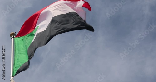 The flag of Sudan is captured in close-up. The flag of Sudan fluttering against the blue sky is the national symbol of Sudan. Great for news. The video is presented in 4K format.