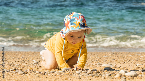 Baby Playing on the Beach Wearing Sun Hat and UV Protective Clothing