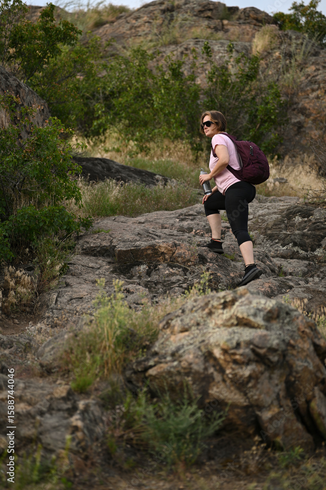Naklejka premium female tourist walking with backpack on beach and rocks