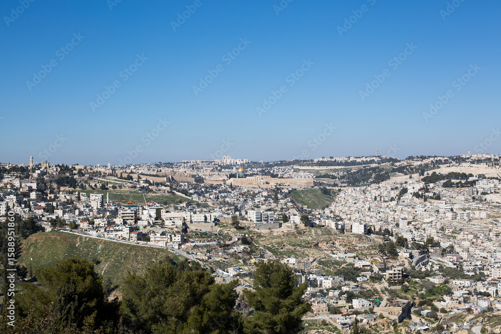 Obraz premium Panoramic view of Jerusalem, Israel with the historic Old City, Dome of the Rock, and surrounding residential neighborhoods under clear blue sky.