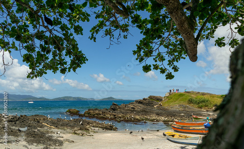 Praia do Forte, Rio de Janeiro, seen from under a tree, with lots of rocks, boats and a beautiful blue sky.-Editar