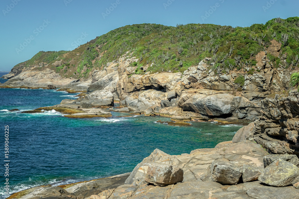 Obraz premium Top view of the back of Praia das Conchas. With large rocks and mountains in the background. Near the city of Cabo Frio, Rio de Janeiro