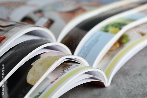 Different open magazines on grey table, closeup