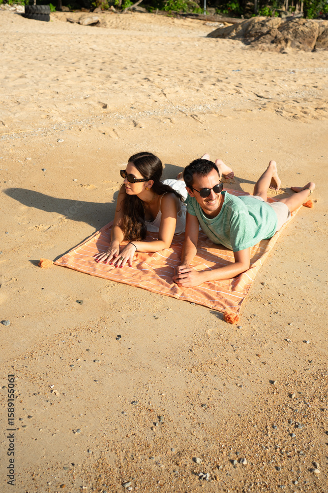 Fototapeta premium Couple lying on beach towel enjoying summer vacation