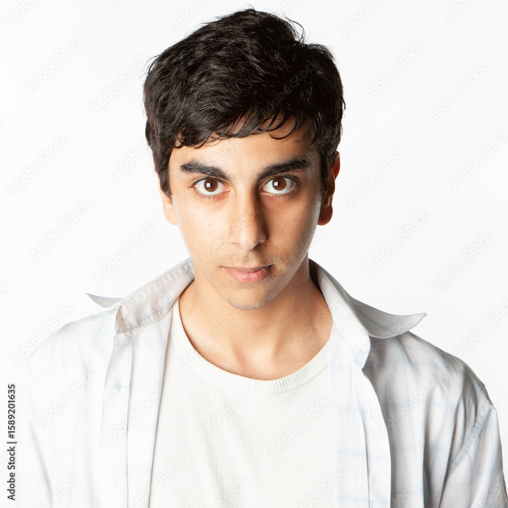 Obraz premium Teenagers: Confidence. A strong direct look from a late teenage boy of Indian heritage isolated against a neutral background. From a series of related images.