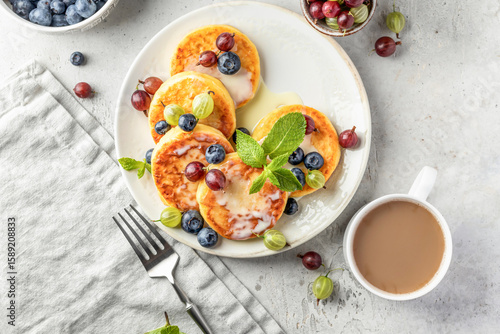 Cottage cheese pancakes with berries and condensed milk top view. Homemade dessert syrniki for healthy breakfast