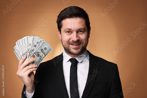 Fototapeta Happy greedy banker with dollar banknotes on golden background
