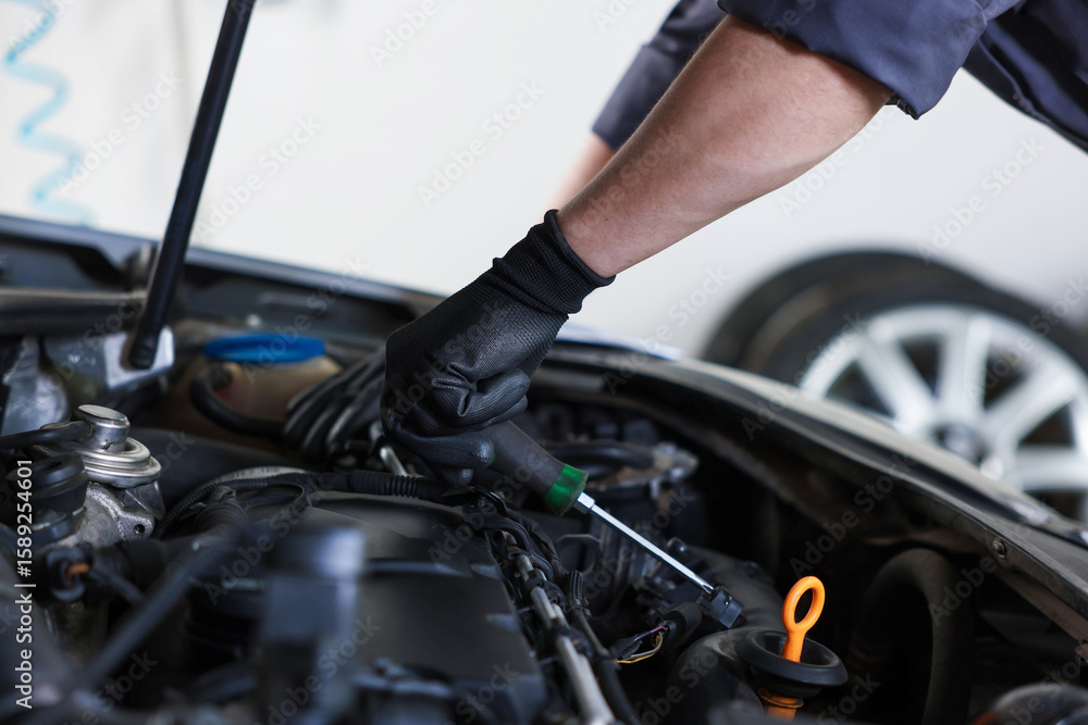 Auto parts. Professional mechanic with screwdriver fixing car indoors, closeup Auto parts. Professional mechanic with screwdriver fixing car indoors, closeup
