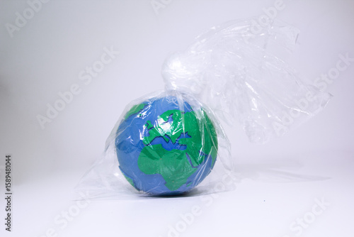 Planet Earth Suffocating in Plastic Bag Wrapper. Earth globe tightly wrapped in clear plastic bag symbolizing environmental crisis and plastic pollution impact. Plastic waste problem concept.