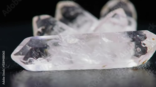 Clear quartz crystal points on a dark surface with water droplets