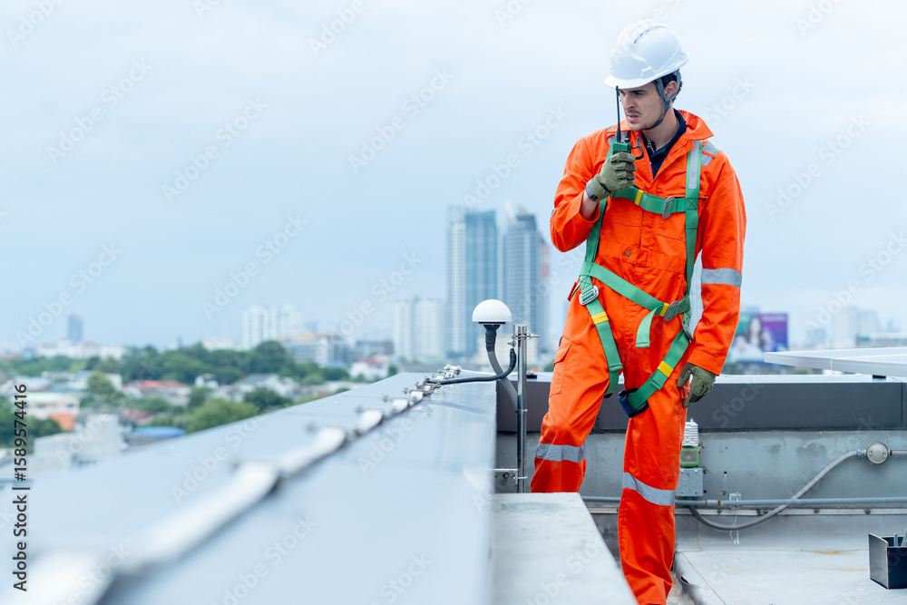 © narong - Professional technician worker or engineer use walkie-talkie to discuss with co-worker near solar cell panel during check or maintenance in area of factory or rooftop building.