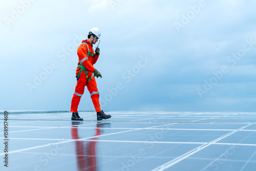 Technician or factory worker use walkie talkie to contact co-worker and also walk along the way to  maintenance rooftop solar cell system with cloudy sky.
