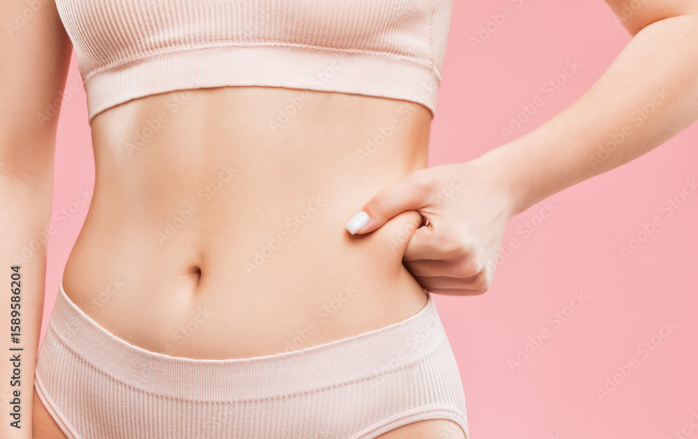 Girl pulls the skin on the abdomen and on the hips showing the body fat. Treatment and disposal of excess weight, the deposition of subcutaneous fat. Girl pulls the skin on the abdomen and on the hips showing the body fat. Treatment and disposal of excess weight, the deposition of subcutaneous fat.