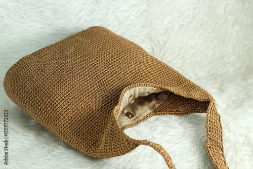 Crocheted handmade milky brown bag on furry white blanket.