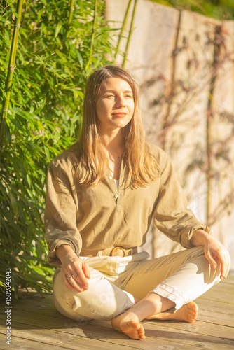 Barefoot Woman Meditating on Wooden Deck in Morning Sunshine