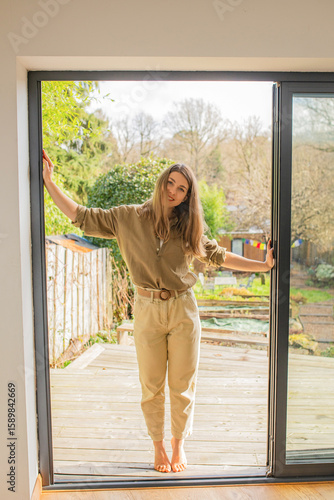 Relaxed young woman enjoying fresh air at home entrance to garden