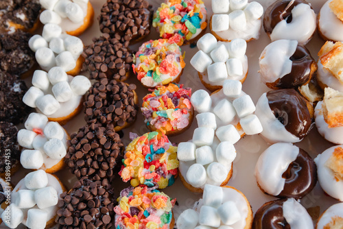 Quadro su tela Colorful assortment of decorated doughnuts with various toppings at a festive di