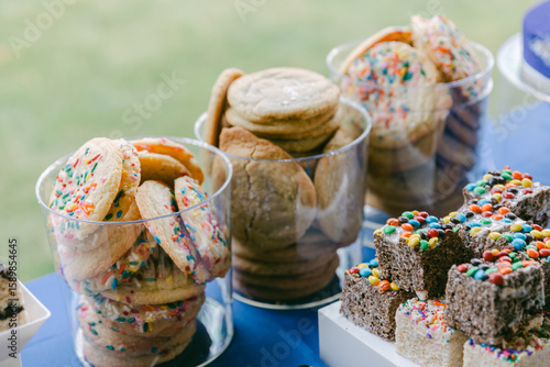 Tablou pe pânză Colorful cookies and treats displayed at a festive outdoor gathering with a chee
