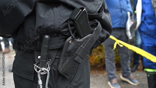 A gun on a policeman's belt on the protest. Pistol in the holster of a member of the special police forces. Gun and bat of police officer. 
