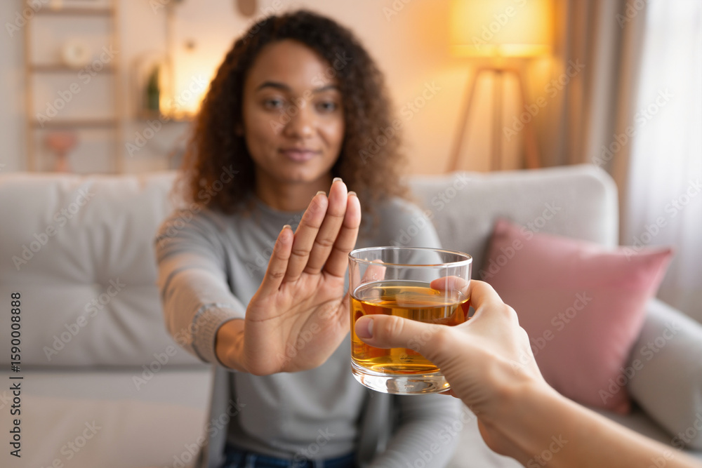 Woman declining drink while sitting on sofa in cozy living room Woman declining drink while sitting on sofa in cozy living room